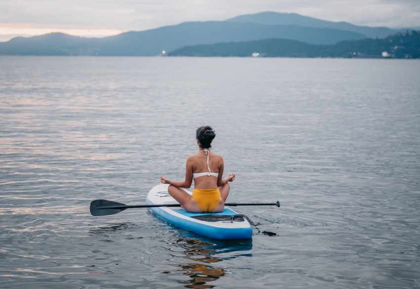 A girl in yoga pose on a SUP-board in the mid-sea