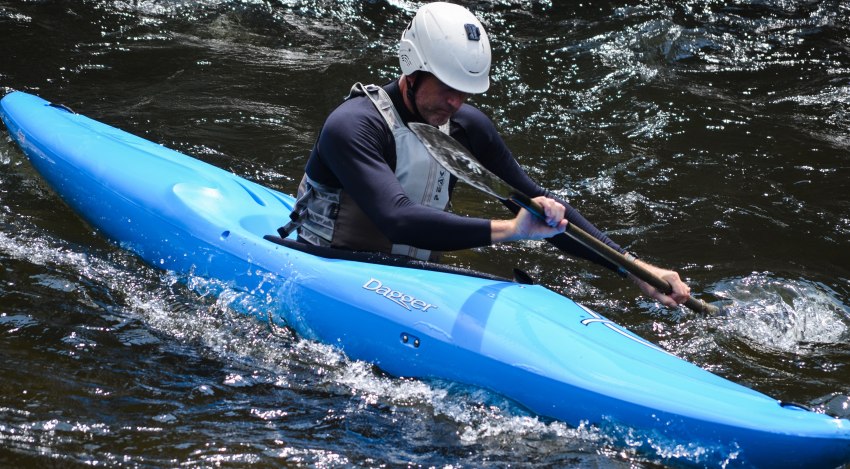 A man in a blue kayak paddling in the whitewater