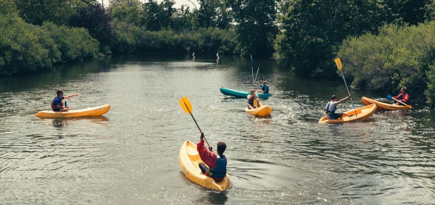 A group of young paddlers exercising in their small boats on the river 