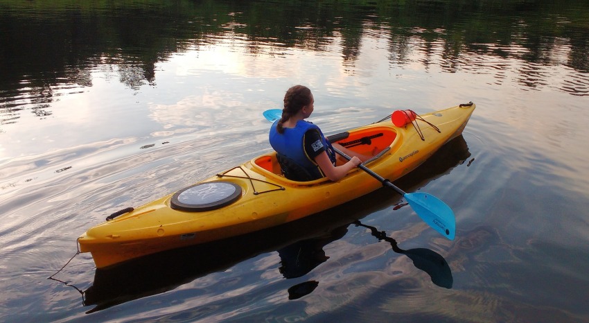 A girl with a paddle in a yellow kayak on the water