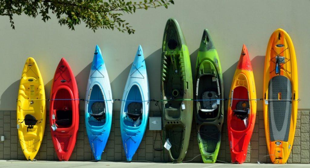 Colorful kayaks of different types leaning against the wall