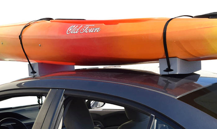 An orange kayak resting on two roof foam carriers