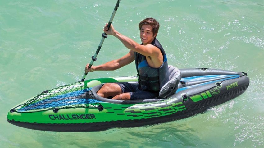 A young man paddling his green inflatable kayak on the water 