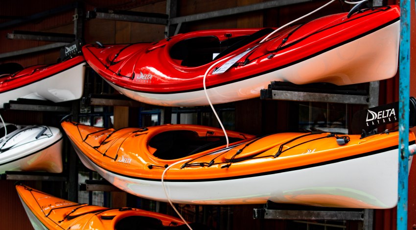 Red and orange kayaks stored on a rack indoors