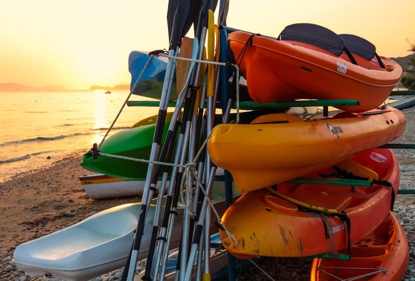 Multi-color kayaks and paddles stored on a rack on the shore 