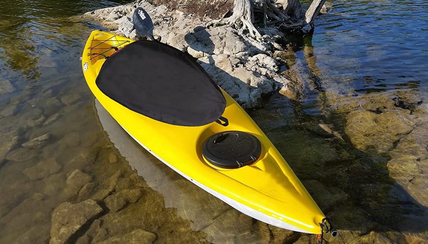 A yellow kayak with a black cockpit cover parked on the shallow water