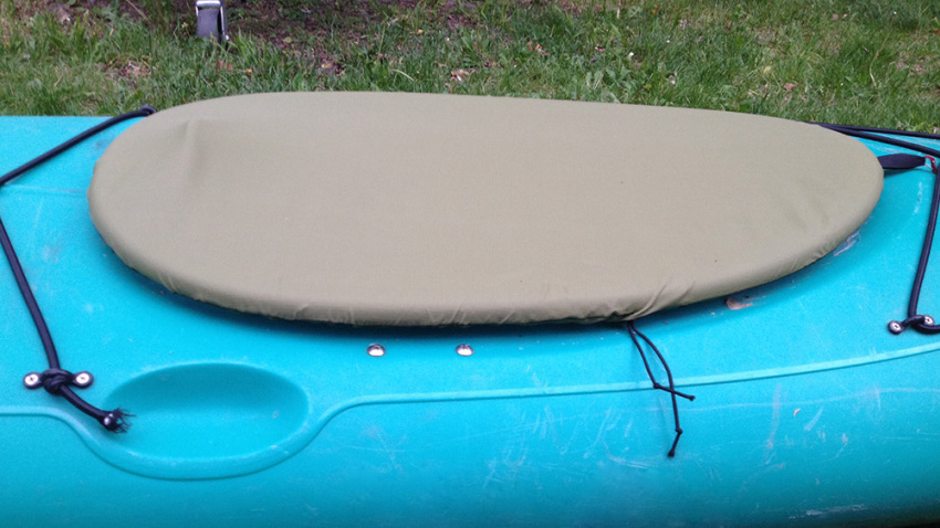 A grey cover on a blue kayak's cockpit