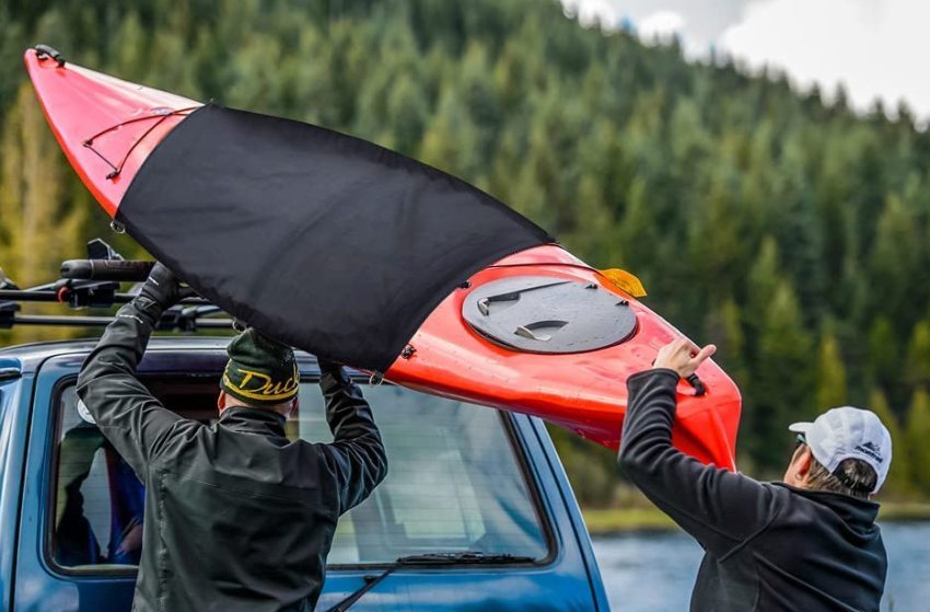 Two men loading a red kayak on a car roof