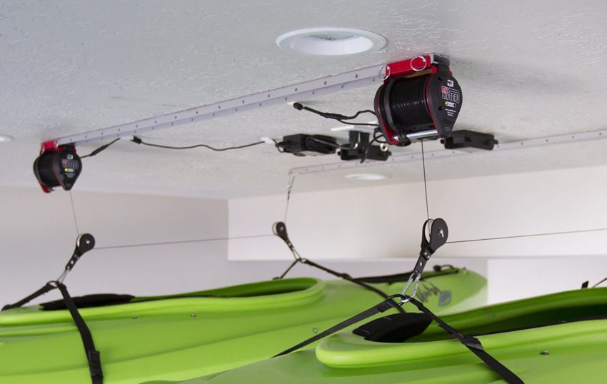 Motorized kayak hoist holds two green kayaks close to the ceiling