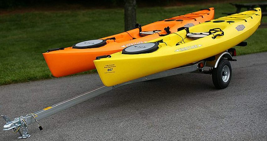 Two kayaks (orange and yellow) resting on a kayak trailer