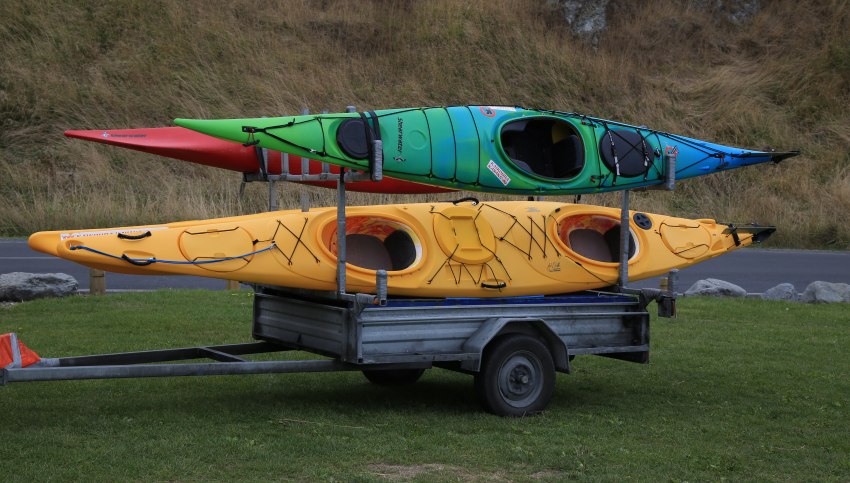 Red, yellow and green-blue kayaks stacked on a kayak trailer