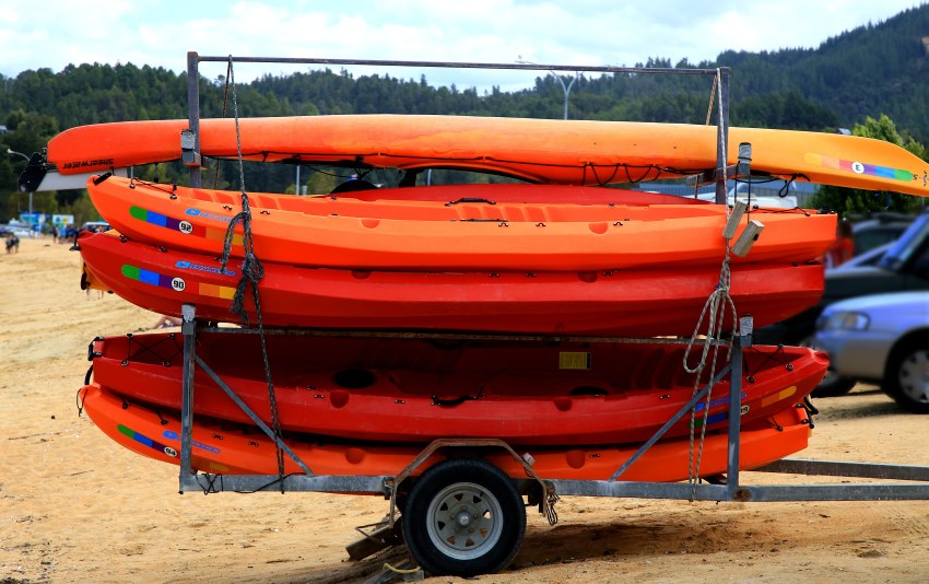 Multiple orange kayaks stacked on a trailer