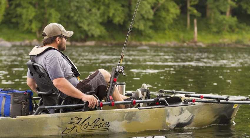 A man with a a fishing rod sits on his Hobie kayak on the water