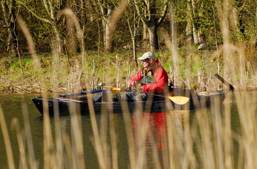 A man in a red jacket and green life vest sitting in a kayak on the water