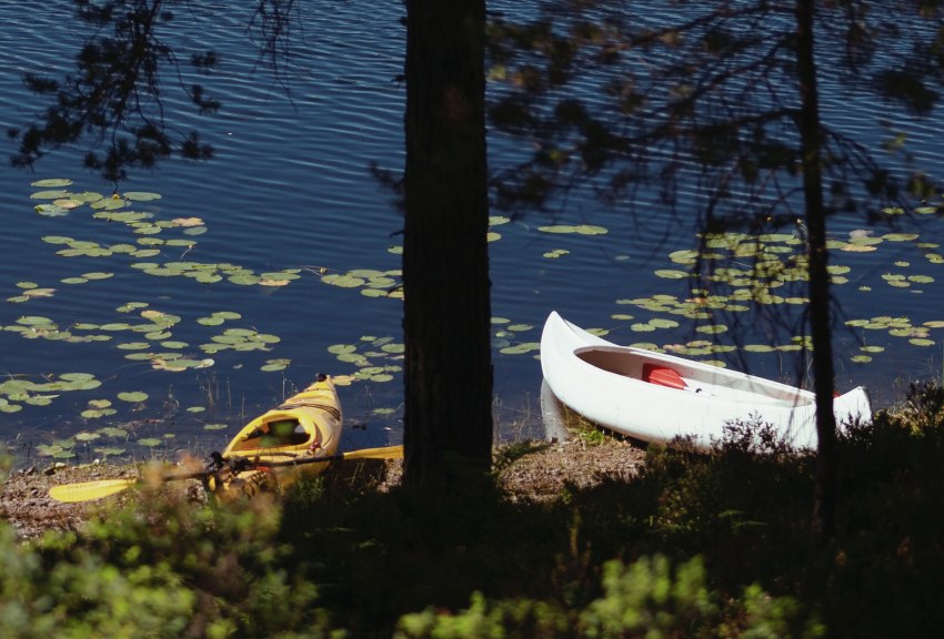 A yellow kayak and a white canoe by the lake