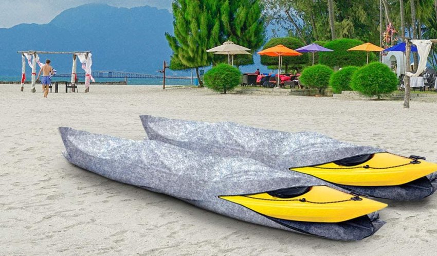 Two yellow kayaks in camouflage bag-style covers lying on the beach