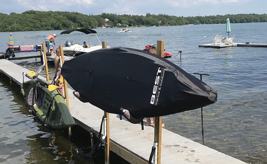A kayak wrapped in black cover, resting on two storage racks on the pier