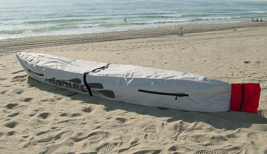 Lonely kayak wrapped in a white cover lying on the beach