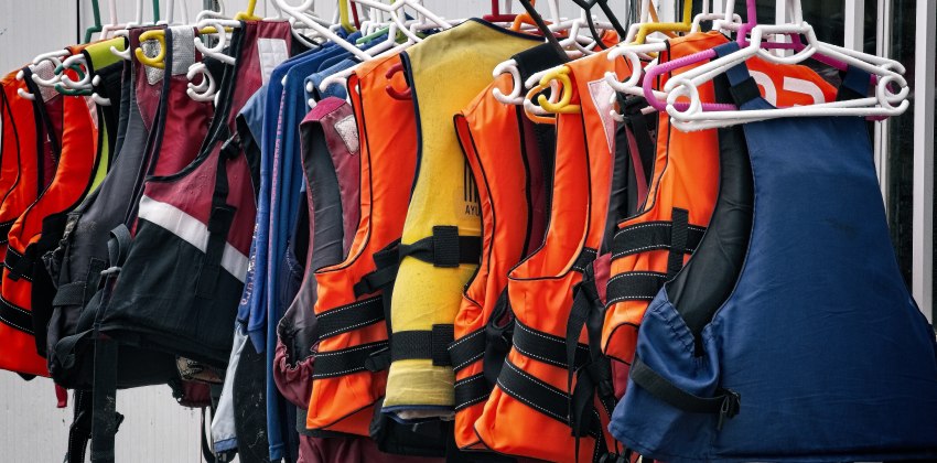 Multiple life jackets of different colors on hangers
