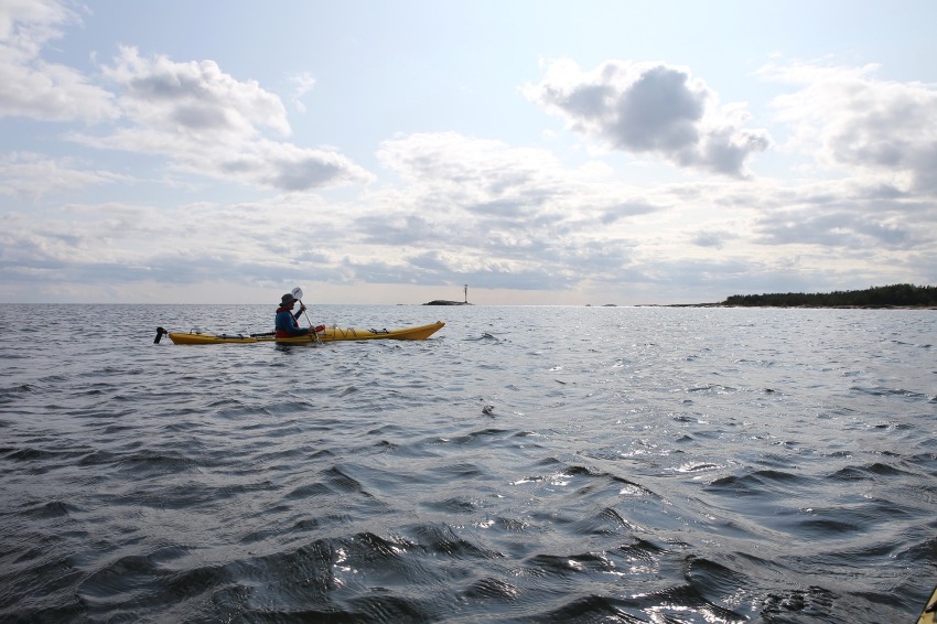 A man paddling a long yellow kayak in the open waters