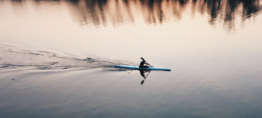 A man paddling his long kayak on the water