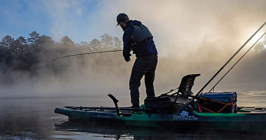 A man standing on a fishing kayak and casting his catch from the water