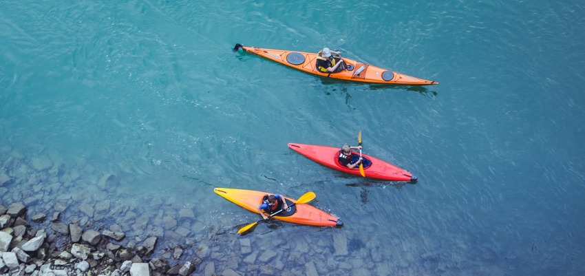 One long and two short kayaks with paddlers on the water