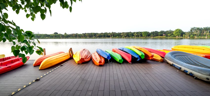 Multiple kayaks of different colors lie on  the dock