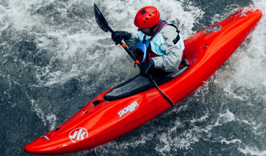 A man paddles his red kayak in the whitewater