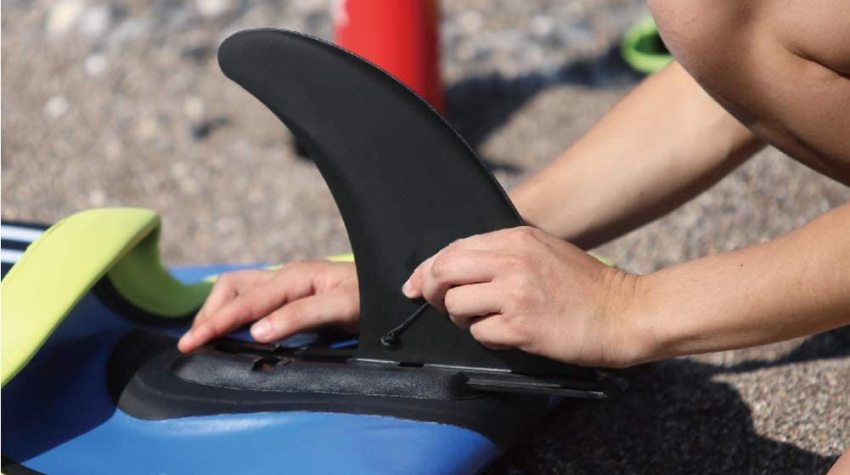 Someone attaches a black skeg to a kayak hull