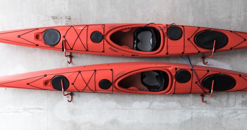 Two long red kayaks rest on the wall storage frames