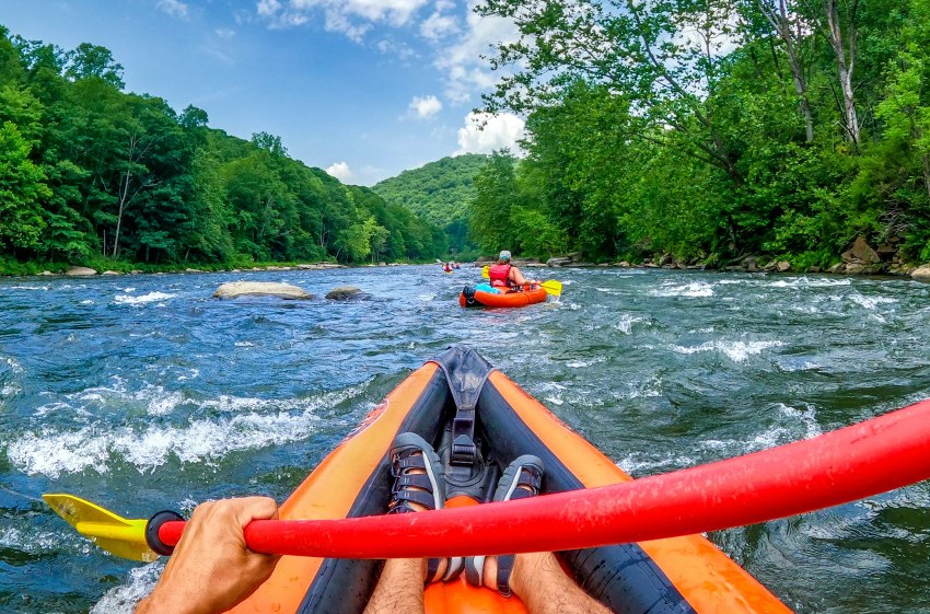 A man paddles an orange kayak in the whitewater