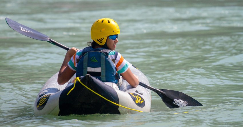 A young paddler sits inside an inflatable kayak on the water