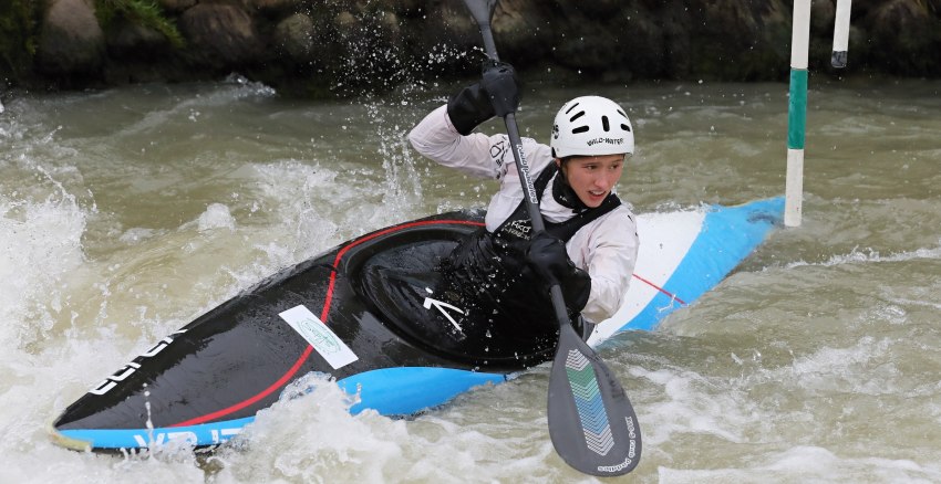 A young paddler rolls a kayak in the white water