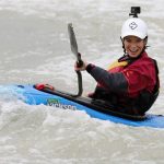 A happy young lady paddles her kayak in the whitewater