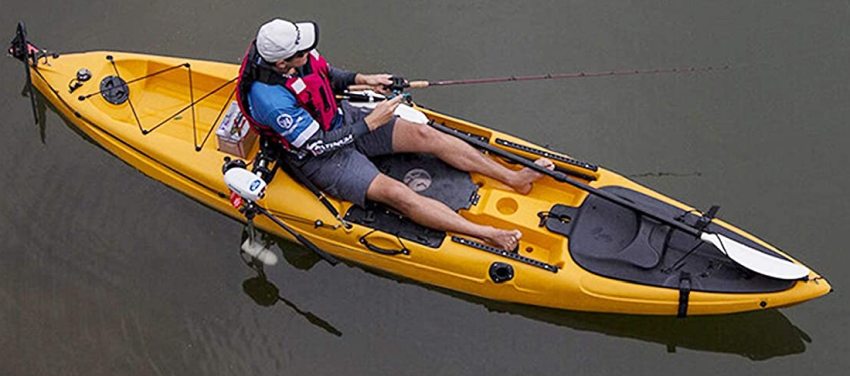 A man fishing from a yellow sit-on-top kayak with a side-mounted trolling motor