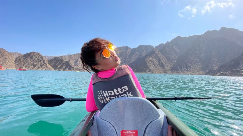 A woman sends a kiss during her kayak trip along the mountainous coast