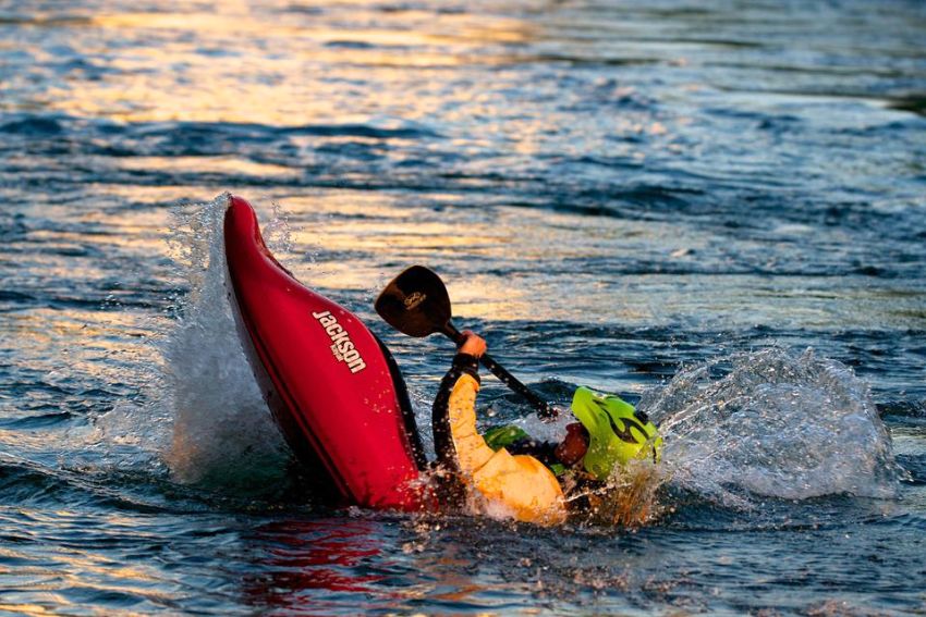 A man in a red kayak capsizes in the water