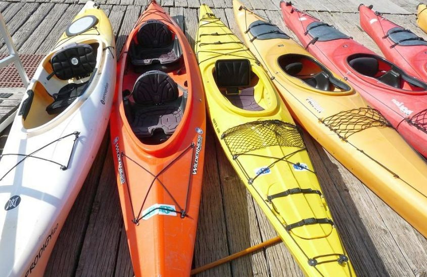 Multiple sit-in kayaks of different colors lying on the pier