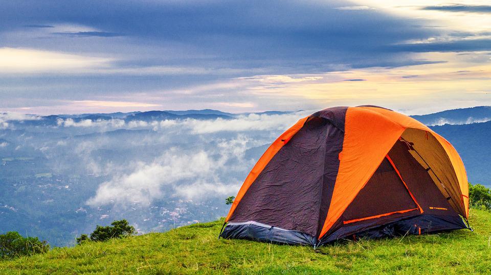 an orange and black tent stands on the hill with breathtaking view
