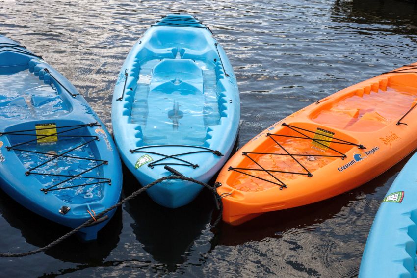 Three sit-on kayaks of different colors on the water