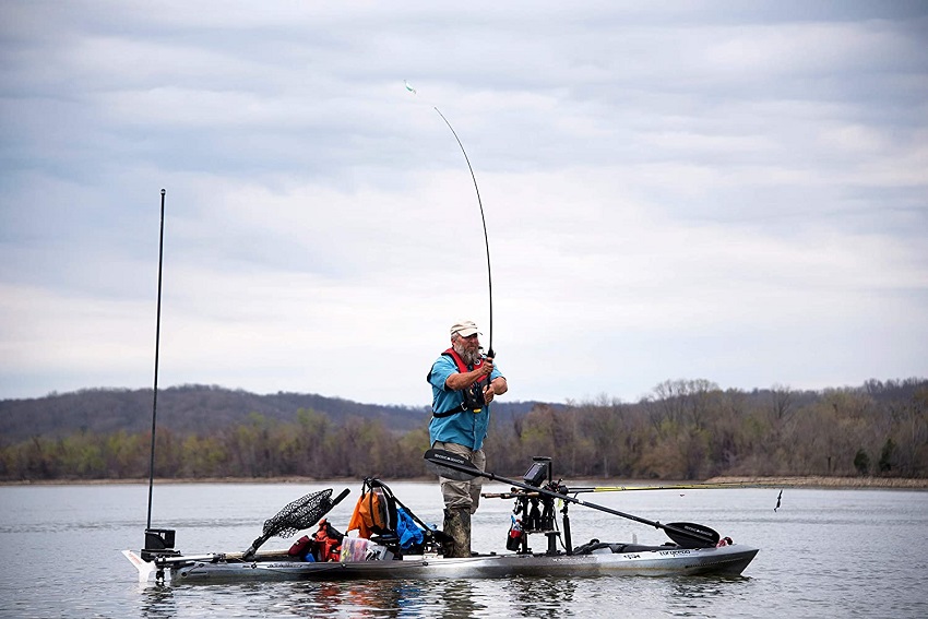 An angler casts a line, standing on a sit-on kayak packed with fishing gear