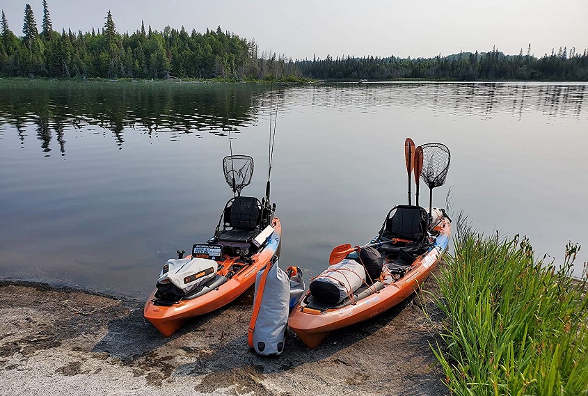 Two sit-on kayaks with fishing gear parked on a lake shore