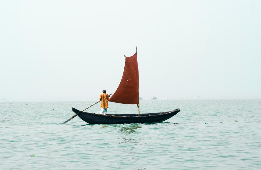 A man sails a lonely boat in the open sea