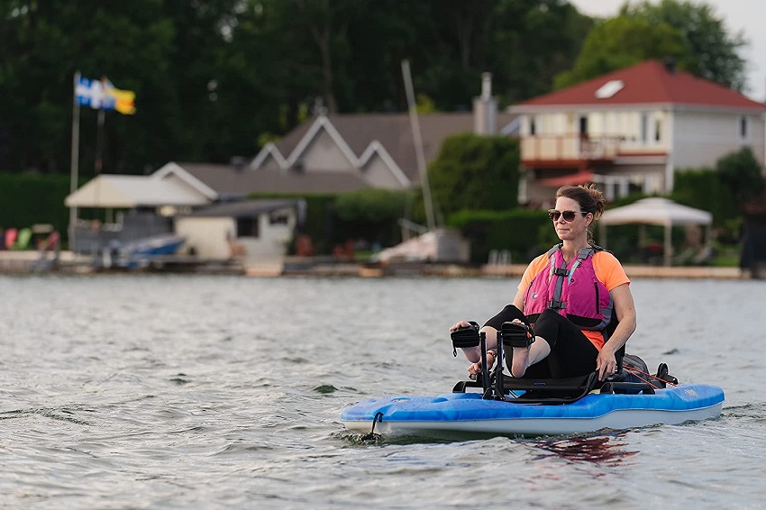 A woman pedals a blue kayak on the water