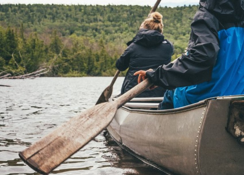 A man and a woman paddle a tandem aluminium canoe