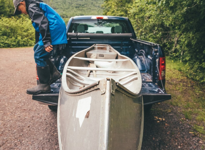 A man unloads his aluminium canoe from a pickup truck