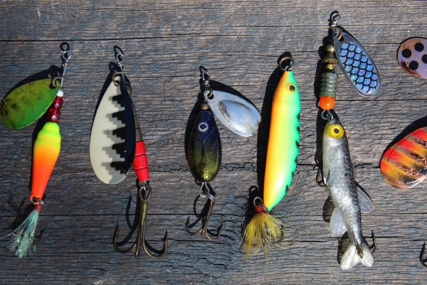 Fishing lures of different colors lying on a wooden surface