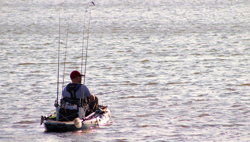 An angler fishes from his kayak in the open sea