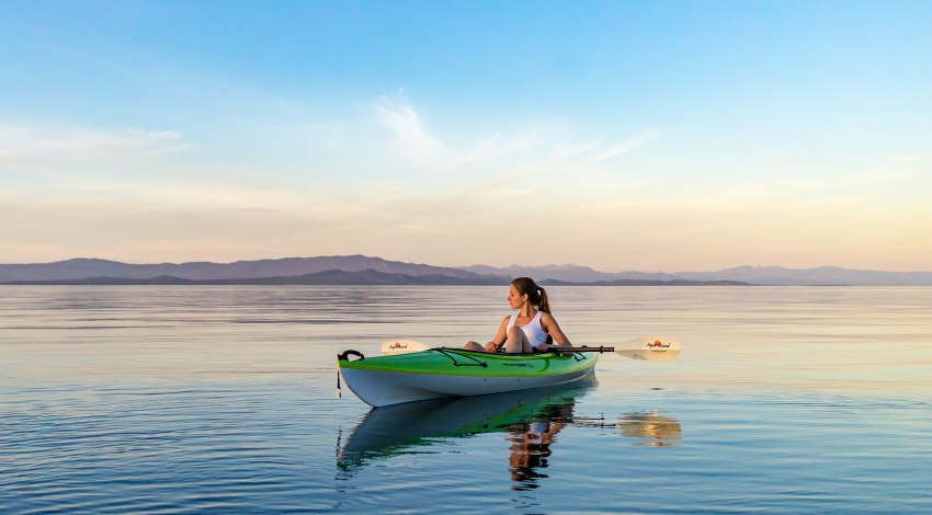 A girl in a green and white kayak on the water
